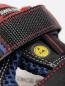 Preview: The image displays a detailed section of a shoe. It is black with red and blue accents. A wide strap made of textured material holds the shoe together, and a yellow logo is visible.