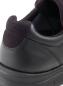 Preview: Das Bild zeigt die Rückseite eines schwarzen Sneakers. Der Schuh besteht aus einer glatten Lederoberfläche und hat eine gepolsterte, dunkelblaue Einstiegskante.