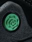Preview: The image shows a black shoe with a round, green detail in the shape of a curled rose. The surface appears textured and slightly rough.