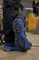 Preview: Das Bild zeigt die Unterseite eines blauen Schuhs auf einem Boden. Die Sohle hat ein markantes, rutschfestes Profil mit verschiedenen Mustern und Linien, die für guten Halt sorgen.