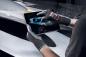 Preview: A person is wearing gray gloves and holding a tablet displaying an image of a vehicle. The background is dark and shows parts of a car.