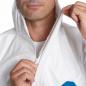 Preview: A man puts on a white, lightweight suit with a zipper. He is holding the zipper and stands against a neutral background. Half of his face is visible.