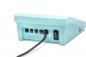 Preview: The image shows the back of a turquoise-colored device. It has multiple ports for cables and a power switch. A black cable is plugged in. The shape is rectangular and flat.