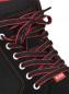 Preview: Das Bild zeigt einen schwarzen Schuh mit roten Schnürsenkeln. Die Schnürsenkel sind aufwendig gebunden und verlaufen durch weiße Ösen. Ein kleiner roter Aufnäher ist sichtbar.