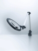 Preview: The image shows a flexible magnifying lamp with a large, round light ring. It stands on a stable base and has an adjustable arm that positions the lamp in various orientations.