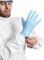 Preview: A man in a white protective suit is putting on a blue rubber glove. He is wearing safety goggles and focusing on the task.