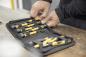 Preview: In the picture, you see hands rummaging through a toolbox with yellow and black tools. The box is placed on a table and contains various screwdrivers and pliers.