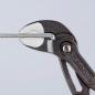 Preview: The image shows a pair of metal tongs with a diamond-shaped gripping surface. It is holding a narrow, straight object in the middle. The background is uniformly light.