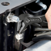 Preview: The image shows a hand holding a black Knipex plier, working on a screw on a metallic object. The background is industrial and metallic.