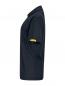 Preview: The image shows a black polo shirt in profile. It has a classic collar and short sleeves. There is a yellow label on one sleeve. The fabric appears slightly textured.