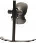 Preview: The image shows a black, round computer camera attached to a sturdy, vertical holder. The holder has a curved base. The camera lens faces forward.