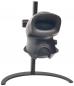 Preview: The image shows a black optical device on a stable stand. It has a round opening at the front and a side button. It is designed to be compact and slim.