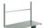 Preview: The image displays a simple, gray table with two vertical, metallic supports on each side. A horizontal bar runs along the top of the supports.