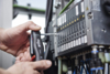 Preview: A craftsman is working with a screwdriver on a machine control. The control has multiple switches and cables that are visible. It is a technical environment.