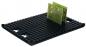 Preview: The image displays a black, rubberized mat with many small, round bumps. On it lies a green circuit board, which stands out due to its rectangular shape and several patterns.