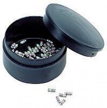 Das Bild zeigt eine gelbe, runde Box mit einem transparenten Deckel. Die Box ist geöffnet und enthält kleine, schwarze Gegenstände, die verstreut sind.