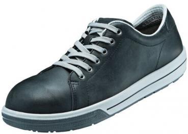 The shoe is a black, low-cut leather sneaker with gray laces. The sole is white with a gray bottom, simple and sporty.