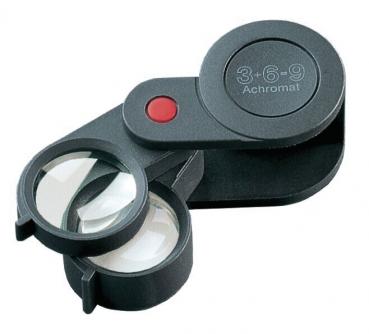 The image shows a black magnifying glass with two lenses: one larger, round lens and a smaller one. It features a red button and a compact, foldable design.