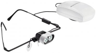 Das Bild zeigt eine spezielle Brille mit zwei kleinen, hellen LED-Lichtern vorne. An einem Kabel ist ein weißes Steuergerät befestigt. Die Brille hat schwarze Bügel.