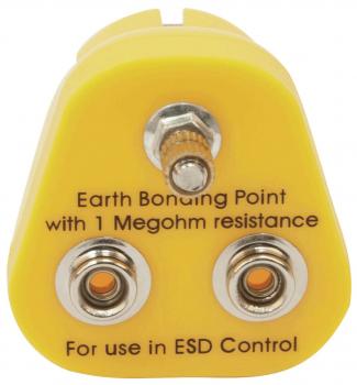 The image shows a yellow plug with a triangular shape. At the top is a screw, below are two round contacts with orange centers. Labeling for grounding and ESD control.