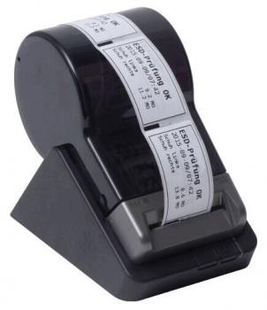 The image shows a black label printer mounted on a stand. It has a roll of labeled adhesive labels, which are partially visible and protruding horizontally.