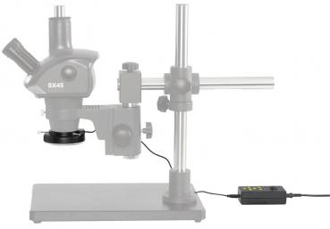 The image shows a microscope with a stable metal base. It has two eyepieces and a stage for the object. Next to the microscope is a control panel with buttons.
