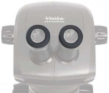 Das Bild zeigt ein Mikroskop mit zwei runden Okularen. Die Oberfläche ist glatt und oval. Oben steht der Schriftzug "Vision Engineering". Es ist ein technisches Gerät zur Vergrößerung von Objekten.