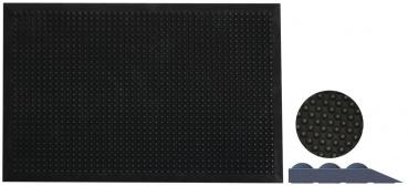 Das Bild zeigt eine große, schwarze Matte mit vielen kleinen Erhebungen in gleichmäßigem Muster. Daneben ist eine kleine runde Matte und ein dreieckiges Element zu sehen, ebenfalls in Schwarz.