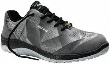 The shoe is sporty, gray with a modern, structured design. It has a light, flexible sole and black laces. The brand 