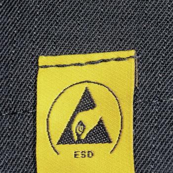 Das Bild zeigt ein gelbes Etikett mit einem schwarzen Symbol in Form eines Dreiecks und einer Hand. Darunter steht "ESD". Der Hintergrund ist aus dunkler Denim-Textur.