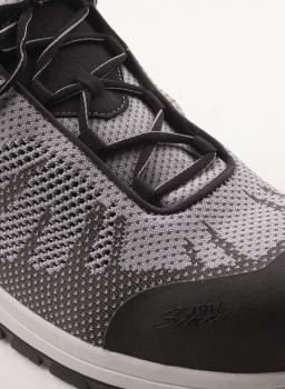 Das Bild zeigt einen sportlichen Schuh in Grau und Schwarz mit atmungsaktivem Netzmaterial. Die Schnürsenkel sind schwarz, und die Sohle ist leicht erhaben.