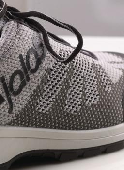 Das Bild zeigt einen grauen Sport- oder Laufschuh. Er hat ein atmungsaktives, gestricktes Obermaterial mit einem dezenten Muster und grauen Schnürsenkeln. Der Schuh hat eine helle Sohle.