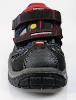 The image shows a black sports shoe with Velcro fastenings and red details. The sole is sturdy with a deep tread, ideal for outdoor activities.