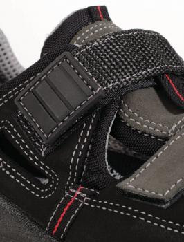 The image shows a black shoe with gray and red accents. It has an adjustable mesh strap and a textured sole. The shoe appears sturdy and sporty.