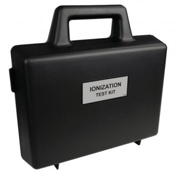 Das Bild zeigt einen schwarzen Koffer mit einem Griff. Auf der Vorderseite befindet sich ein beschriftetes Schild, das "IONIZATION TEST KIT" lautet. Der Koffer ist rechteckig und stabil.