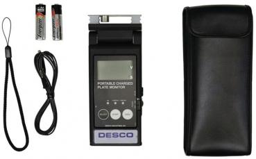 The image shows a portable device, a flat monitor with a digital display. Next to it are two batteries, a cable, and a black bag.
