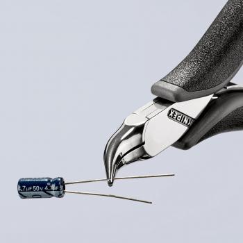 The image shows a precise pair of pliers with a shiny, pointed head holding a blue capacitor with two wire leads in front of it. The background is bright and minimalist.