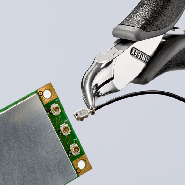 The image shows a pair of pliers holding a fine wire attached to a green circuit board. The circuit board has golden connectors and a silver surface.
