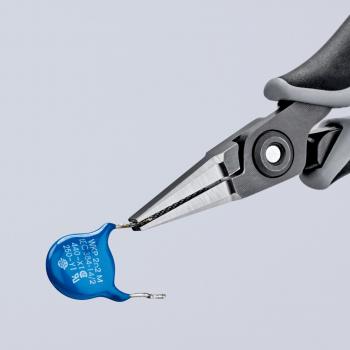 A pair of pliers holds a small blue component, which is round and flat with two connecting wires. The background is bright and unattended, focusing attention on the tool.