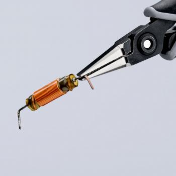 Two pliers grasp a small, cylindrical component with orange wire and metallic ends. The background is bright and lacks detail.