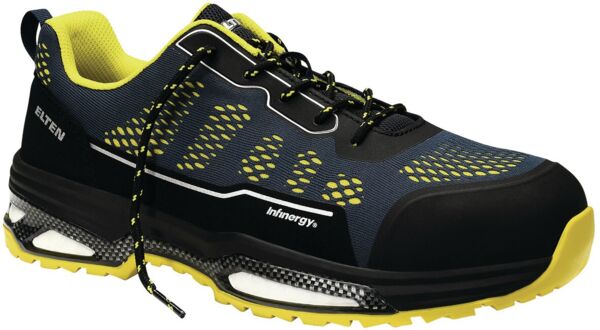 The shoe is black with gray and white accents. It has a modern design, a padded sole, and many small holes for ventilation. The laces are black.