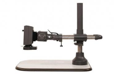 The image shows an optical device on a stable, rectangular table. It has a gray base, a vertical support, and an arm structure with a holder for lens-like objects.