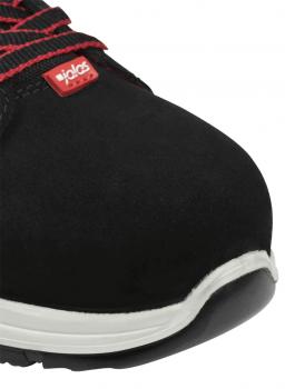 Das Bild zeigt die Vorderansicht eines schwarzen Schuhs mit rotem Logo. Der Schuh hat eine robuste Konstruktion und eine helle, rutschfeste Sohle. Schnürsenkel sind sichtbar.