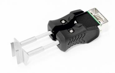 The image displays a unique clamp-shaped plug. It features two metallic, claw-like elements and a rectangular connector on the top. The handle is black and textured.
