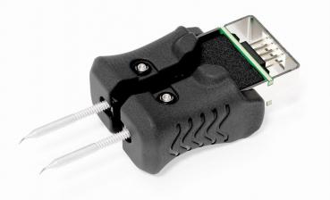 Das Bild zeigt ein elektrisches Messgerät mit zwei Metallsonden und einem schwarzen Kunststoffgehäuse. Oben befindet sich ein Steckplatz mit Pins, der für elektrische Verbindungen genutzt wird.