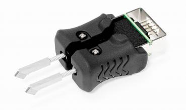 The image shows a black tool that looks like pliers, with two movable metal tips. It has an opening at one end intended for connectors.