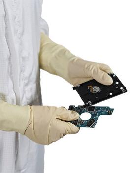 Eine Person in weißen Handschuhen hält zwei Teile eines Computerlaufwerks. Das obere Teil ist schwarz und hat eine runde Öffnung, das untere ist grün mit feinen Schaltkreisen.