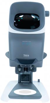 The image shows a medical device for eye examination. It has a large, rounded opening at the front and a stable base. The design is modern and in shades of gray.