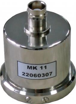 Das Bild zeigt ein metallisches, zylindrisches Bauteil mit einer runden Basis und einem Anschluss oben. Es hat eine glatte Oberfläche und trägt ein Etikett mit der Aufschrift "MK 11" und einer Nummer.