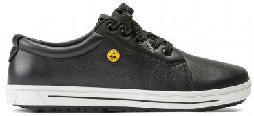 Der Schuh ist ein schwarzer Sneaker aus Leder mit runder Spitze. Er hat eine glatte Oberfläche, eine gelbe Markierung an der Seite und eine weiße Sohle mit leichtem Profil.